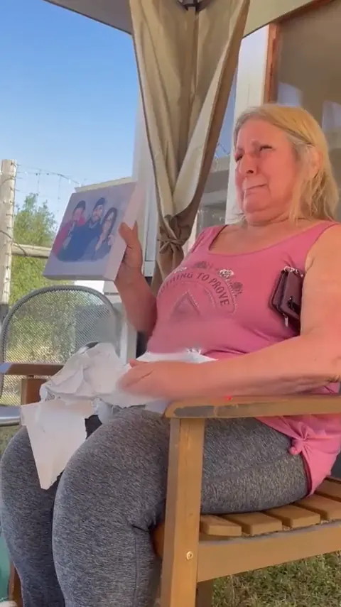 A woman on her porch in tears over a portrait.